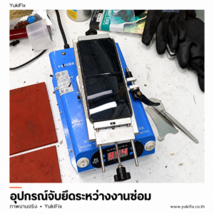 โทรศัพท์จอพับวางบนอุปกรณ์จับยึดสีน้ำเงินระหว่างงานซ่อม
